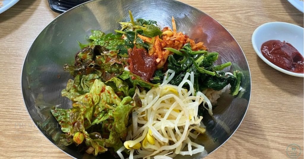 韓国・清州、ユッコリ市場のヨンファポリパプ (영화보리밥) の麦ごはん、ナムルを乗せる